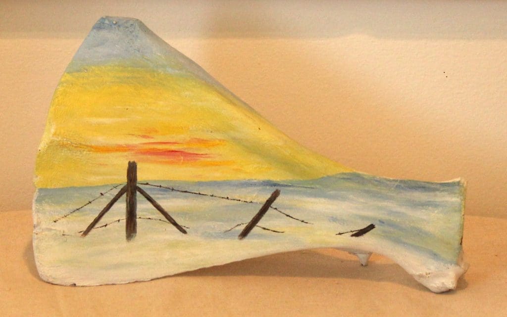 Oil painting by Lise Perrault, on bovine scapula, depicting a barbed wire fence in winter.